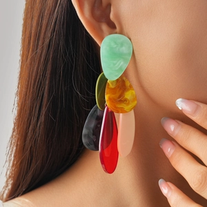 Close-up of oversized acrylic teardrop earrings with multi-color marble texture on a model
