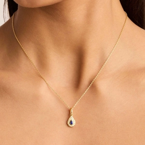 Collana d'oro in acciaio al titanio con ciondolo a goccia blu indossata da modella