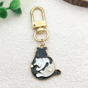 Detail of enamel black and white hugging cats charm with golden keychain ring