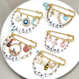 Golden evil eye safety pin brooches featuring lucky charms and BELIEVE DREAM letters