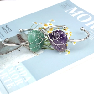 Macro view of handmade wire-wrapped crystal heart bangles in purple and green stones