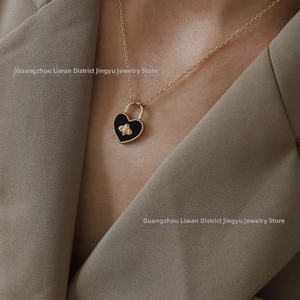 Close-up of golden heart pendant with black enamel and bee relief on a model