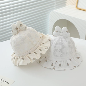 Détail de chapeaux de soleil en dentelle pour bébé avec bords fleuris et nœuds blancs