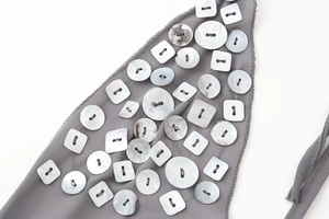 Détail du tissu gris de la robe d'été avec boutons décoratifs géométriques nacrés