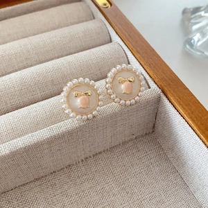 Close-up of vintage flower pearl earrings with pink gem and golden bow in a wood box