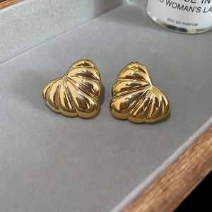 Macro shot of gold-finished heart-shaped earrings featuring textured shell-like radiating ridges