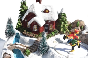 Détail d'un village de Noël miniature avec maison en briques et figurines de patinage
