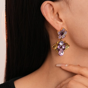 Detail of vintage gold earrings with purple crystals on model ear showing drop pendant