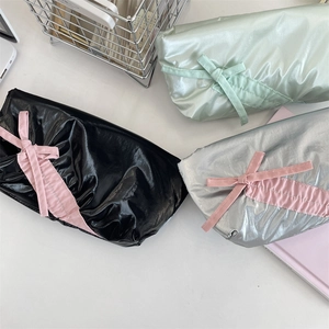 Flat lay of bow-knot pencil cases in black, silver, and green metallic crinkled fabric