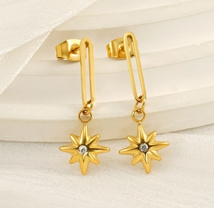 Macro shot of 18K gold plated North Star drop earrings with zircon on white silk