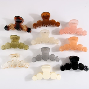 Flat lay of nine minimalist geometric claw clips in varied colors on a white background