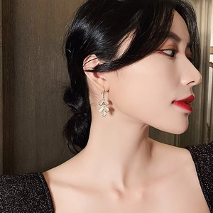 Elegant gold leaf earrings with opal stones worn by a model in a luxury evening setting