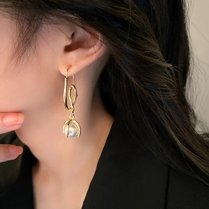 Close-up of elegant gold twisted wire earrings with white pearl pendants on a model