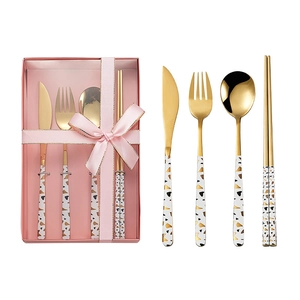 Golden stainless steel cutlery set with black spotted handles in a pink gift box