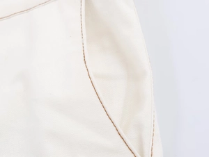 Detail of high-waist flare pants showing contrast stitching and side pocket texture