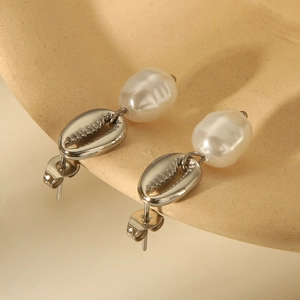 Silver scallop shell earrings with irregular freshwater pearls on beige background