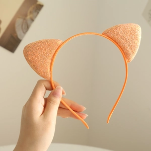 Close-up of a glittery orange cat ear headband held by hand for little girls