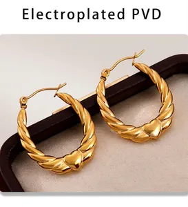 Macro view of gold PVD plated heart twist hoop earrings on premium leather tray