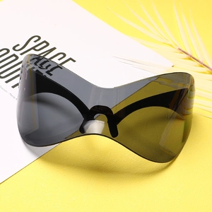 Detail of oversized punk mask sunglasses with grey lenses on a yellow textured background