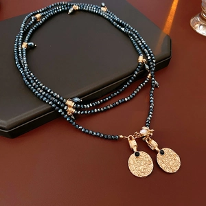 Detail of vintage gold layered necklace with dark blue faceted beads and coin pendants