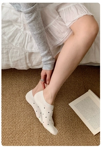 Detail shot of white cotton no-show socks with black polka dots on a cozy indoor background