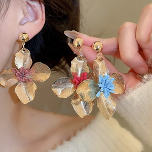 Macro view of gold flower earrings with colorful petals and polished texture details