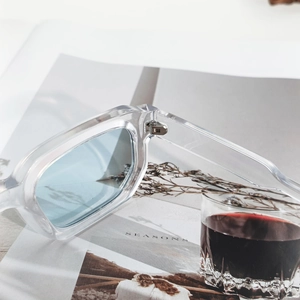 Classic square sunglasses with transparent frames and light blue lenses in a luxury setting