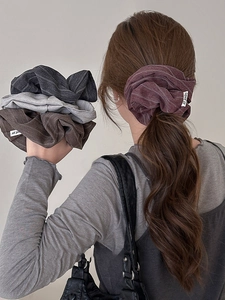 Close-up of striped fabric scrunchies in multiple colors with quality brand label details