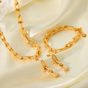 Détail d'une parure de bijoux à maillons en U dorés avec collier et bracelet