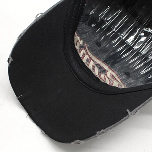 Close-up of distressed brim edges and embroidery on black washed cotton baseball cap