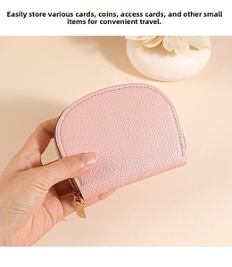 Pink litchi grain leather card holder held in hand with gold zipper closure