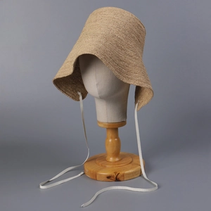 Detail of hand-woven raffia cloche hat with stylish drawstring on a minimalist display