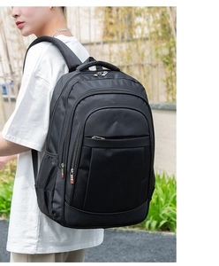 Detail view of black business backpack with padded straps and red cross logo on zipper