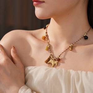 Close-up of a woven horse pendant necklace with tassels and beads on a model