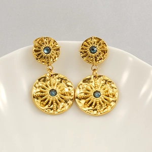 Detail of starburst engraved golden earrings with deep blue gemstones on ceramic tray