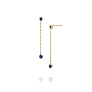Detail of gold long tassel earrings featuring blue turquoise stones on white background