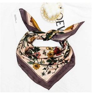 Detailed shot of gold and purple silk scarf with floral and bee prints tied in a bow