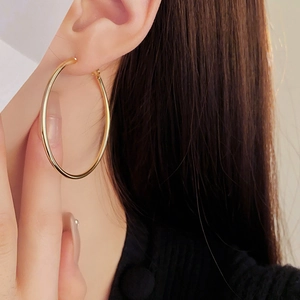 Close-up of a model wearing a large polished gold circular hoop earring for women