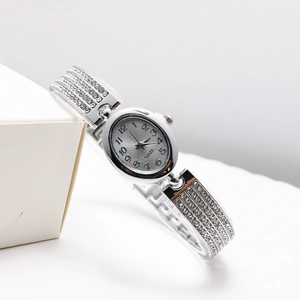 Silver oval quartz watch with full diamond setting and rhinestone bracelet on white background