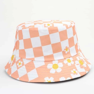 Detail of checkered bucket hat with daisy print pattern on a light orange cotton fabric
