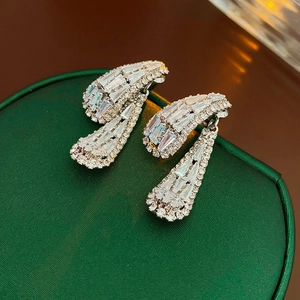 Détail de boucles d'oreilles pendantes en argent avec zircons sur boîte à bijoux en satin