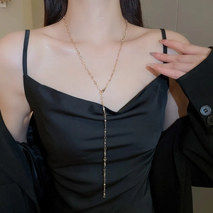 Golden Y-shaped long tassel necklace with heart charms worn by a model in black outfit