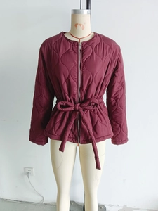 Detail of burgundy quilted jacket featuring wave stitching and a waist tie-belt design