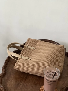 Detail shot of a vintage brown checkered cotton tote bag on a rustic wooden tray