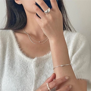 Minimalist silver rings and layered jewelry set worn by a model in soft natural light