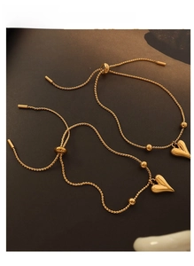 Detail of gold heart pendant bracelets with adjustable slide clasp and spiral chains
