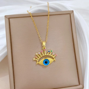 Macro detail of gold evil eye necklace with colorful zircons on beige display board