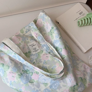 Close-up of floral cotton tote bag with pink and blue rose patterns and white woven label