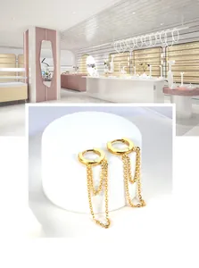 Detail of gold chain tassel earrings on a white stand featuring long vertical chain fringe