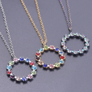 Three circular 18k plated stainless steel necklaces with colorful rhinestones on grey